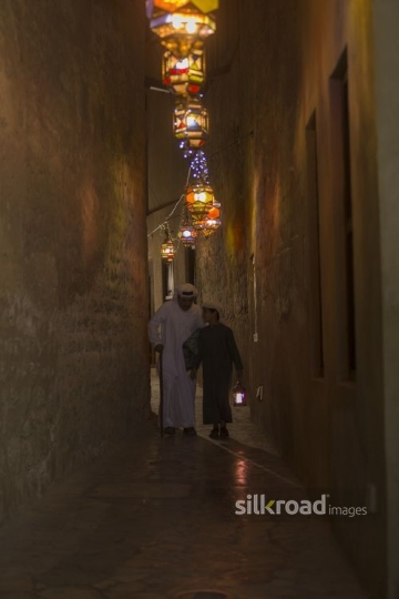 Arab father and son walking through the pathway decorated by Ramadan Lanterns|-