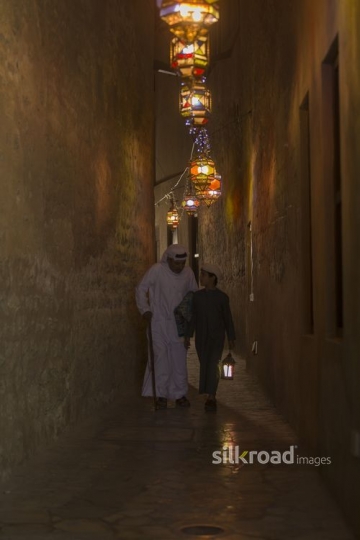 Middle Eastern father carrying a prayer rug while the son is carrying a Ramadan Lantern|-