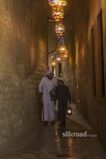 Arab man carrying a prayer rug an the kid is carrying a Ramadan Lantern|-