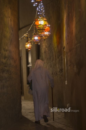 Arab man dressed in a traditional outfit carrying a prayer rug during Ramadan|-