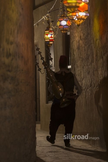 A Middle Eastern Ramadan drink seller strolling along the pathway|-