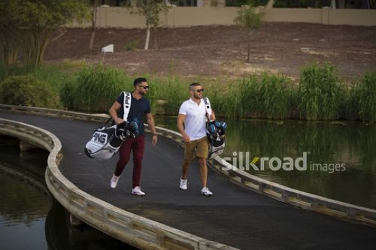 Young Arab men carrying Golf bags walking together|-