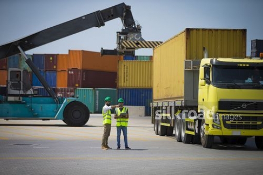 Workers standing at the Port with cargos behind them|-