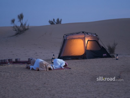 Men praying in the desert