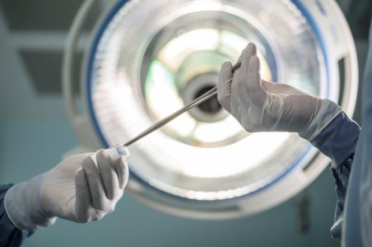 A Surgeon Holding Scissors and Cotton