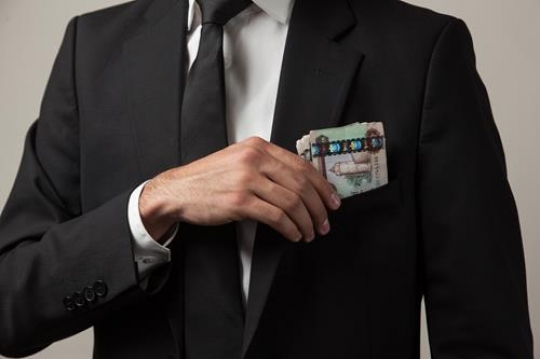 businessman putting money in h