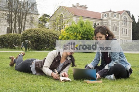 Two girls sitting together outside talking|