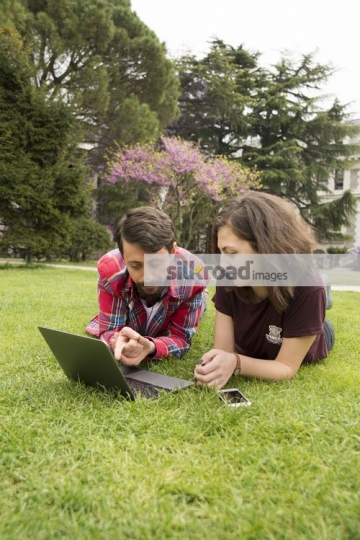 Two students laying on the grass studying
