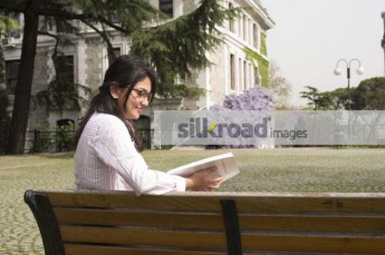 Student studying from a book on campus|