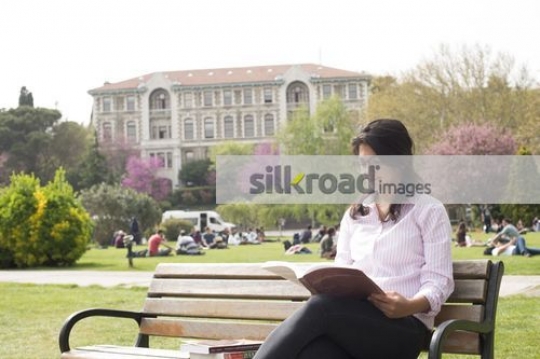 Woman sitting on the bench studying from a book|