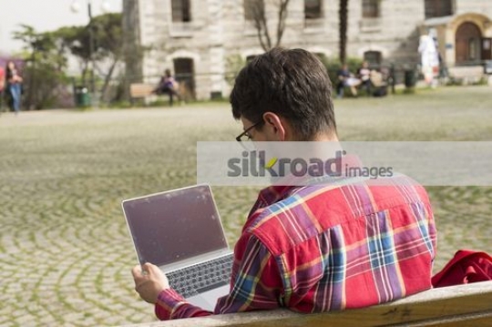 Student studying from the laptop sitting on the bench|