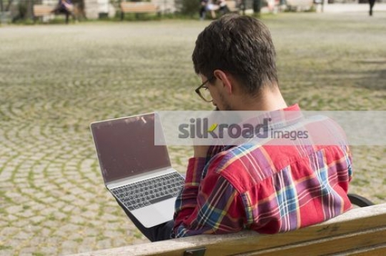 University Student sitting on the bench using the laptop |
