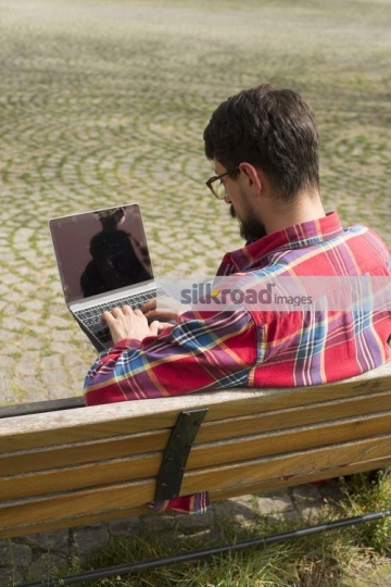 University student sitting on the bench using the laptop|