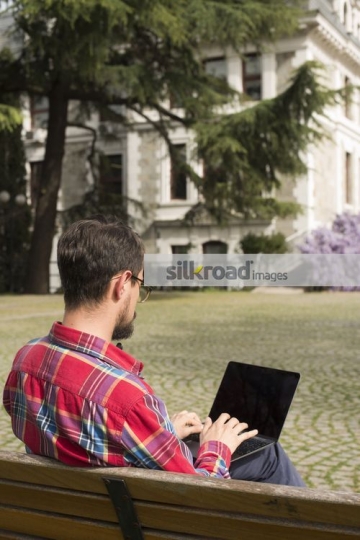 University Student sitting on the bench using the laptop|