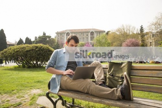 Student studying from the laptop sitting on the bench|