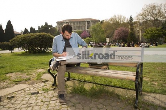 Man sitting on the bench studying from the book|