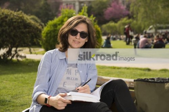 University Student sitting on the bench book in hand|