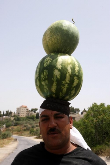 man holding two watermelons on