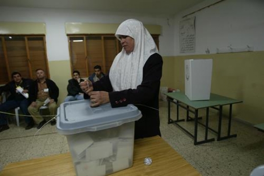 muslim woman putting a voting ballot into the box