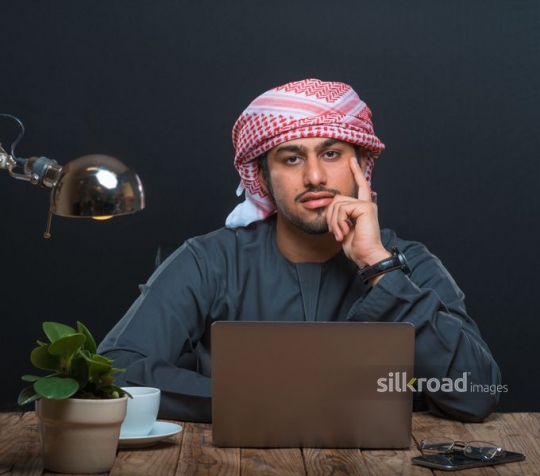 Arabian man thinking behind his laptop