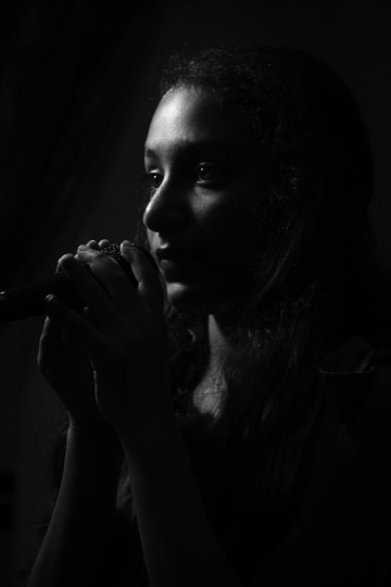 young singer with microphone in darkness