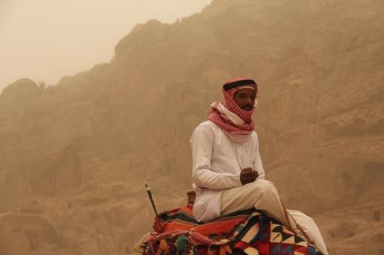 Bedouin sitting on his camel during desert ride in Wadi Rum