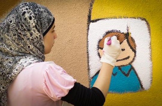 muslim girl drawing on the wall of kindergarten