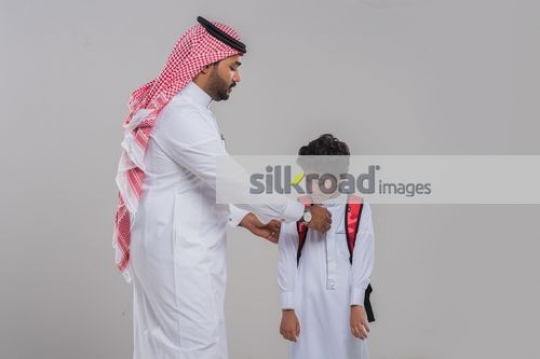 Arab man fixing the young kids kandoura