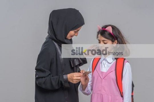 Middle Eastern woman giving the young kid money