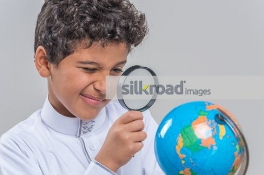 Arab kid using the magnifying glass|