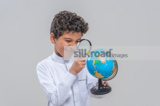 Middle Eastern kid looking through the magnifying glass|