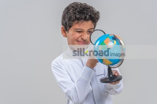Arba kid looking at the globe through the magnifying glass|