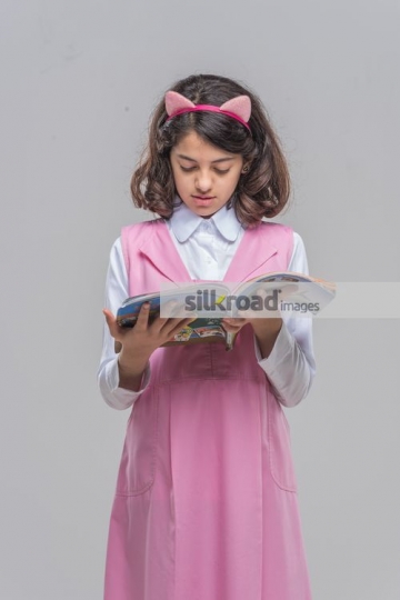 Middle Eastern kid standing reading the book
