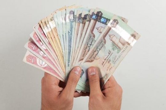 hands with uae dirham currency note