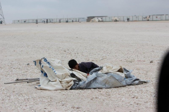 kid by a tent roll in a camp