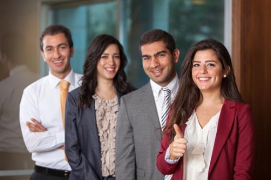 group of four happy executives giving thumbs up