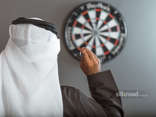 Arabian man aiming at the dart board