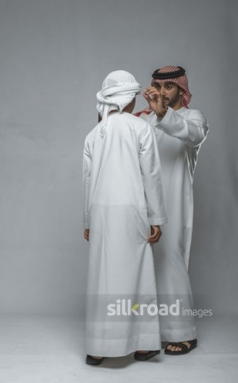 Father fixing traditional head cover of his son
