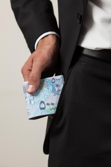 businessman getting a bundle of qatari currency note out of his pocket