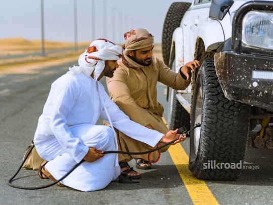 Friends fixing car wheel