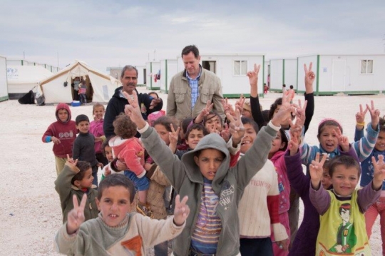 group of kids showing V sign with men from Zaatari refugee camp for Syrian refugees