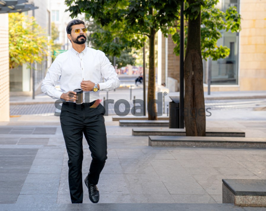 Man Walking Between Modern Buildings with Coffee Cup in Al Abdali Boulevard