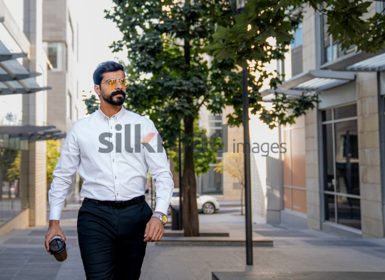 Man Walking Between Modern Buildings with Coffee Cup in Al Abdali Boulevard