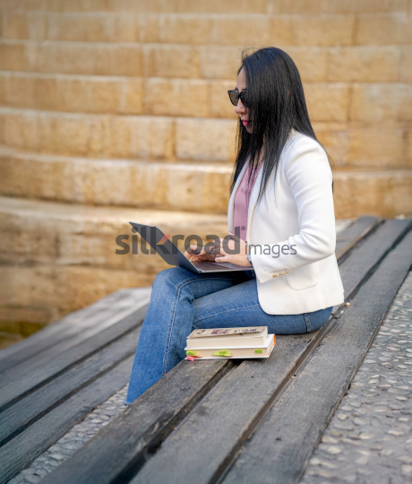 Professional Arab Woman Working with Laptop, Books, and Notebook in Jordan's Al Abdali Boulevard
