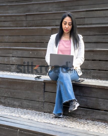 Professional Arab Woman Working with Laptop, Books, and Notebook in Jordan's Al Abdali Boulevard