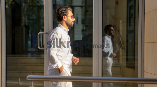 Professional Man Walking Past Glass Door in Morning Light at Al Abdali Boulevard