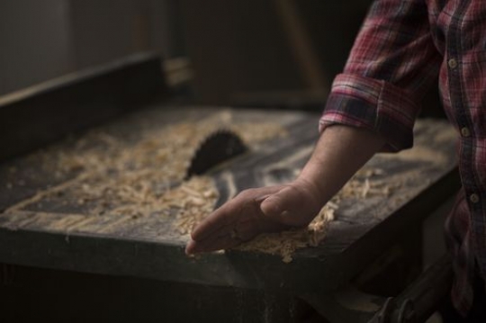 Man cleaning the wood dust from the table