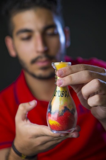Young Expat carrying a traditional sand art souvenir |-