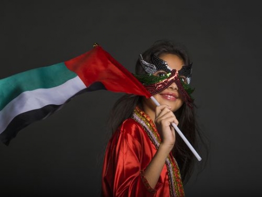 Middle Eastern girl carrying the UAE flag celebrating National Day