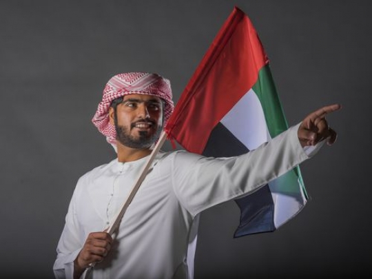Middle Eastern man carrying the UAE Flag|